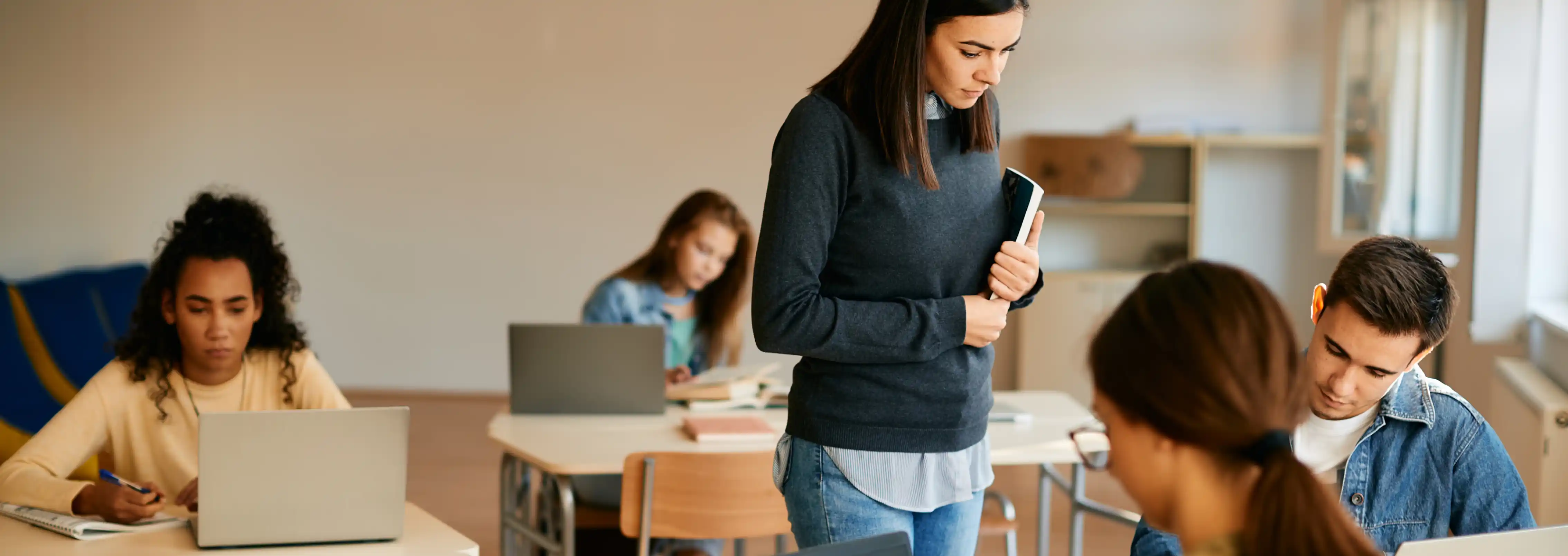 Teacher standing beside student in classroom