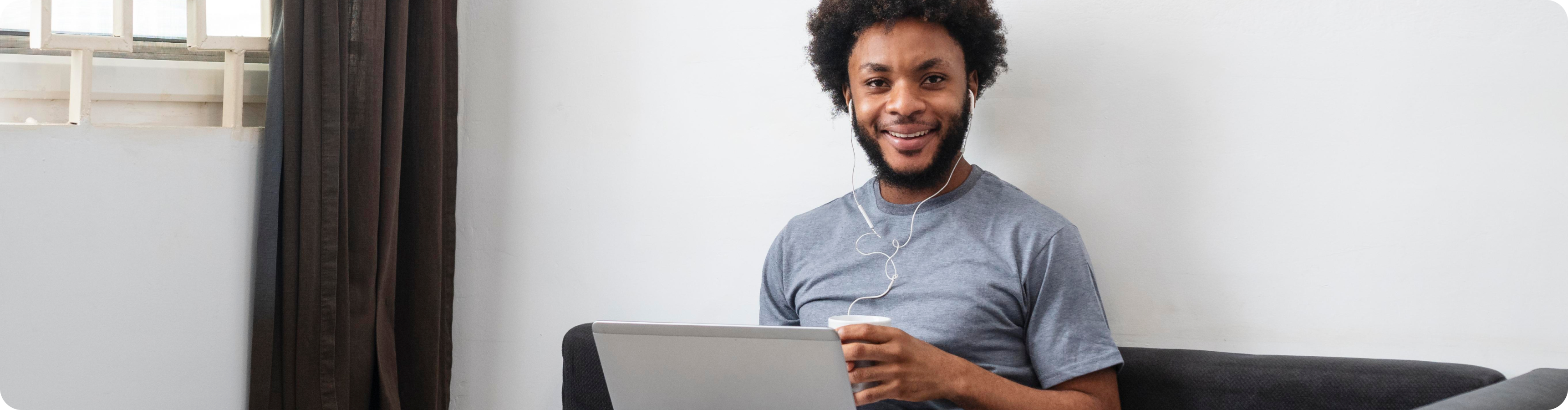 A smiling Black Boy listening something on laptop with earphone